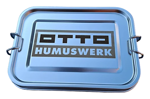 Edelstahl-Brotdose mit Klappverschluss und Gravur des Logos Otto Humuswerk auf dem Deckel.