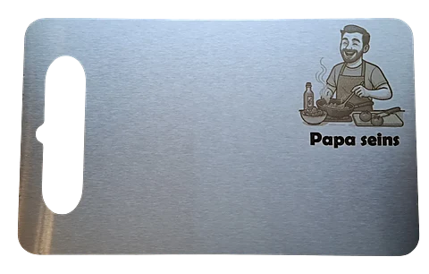 Freigestelltes Schneidebrett mit Gravur eines kochenden Mannes und dem Schriftzug Papa seins.